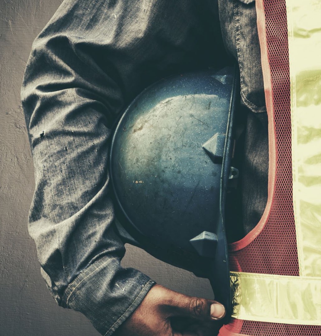 Man holding a protective hat at a facility and construction workplace.